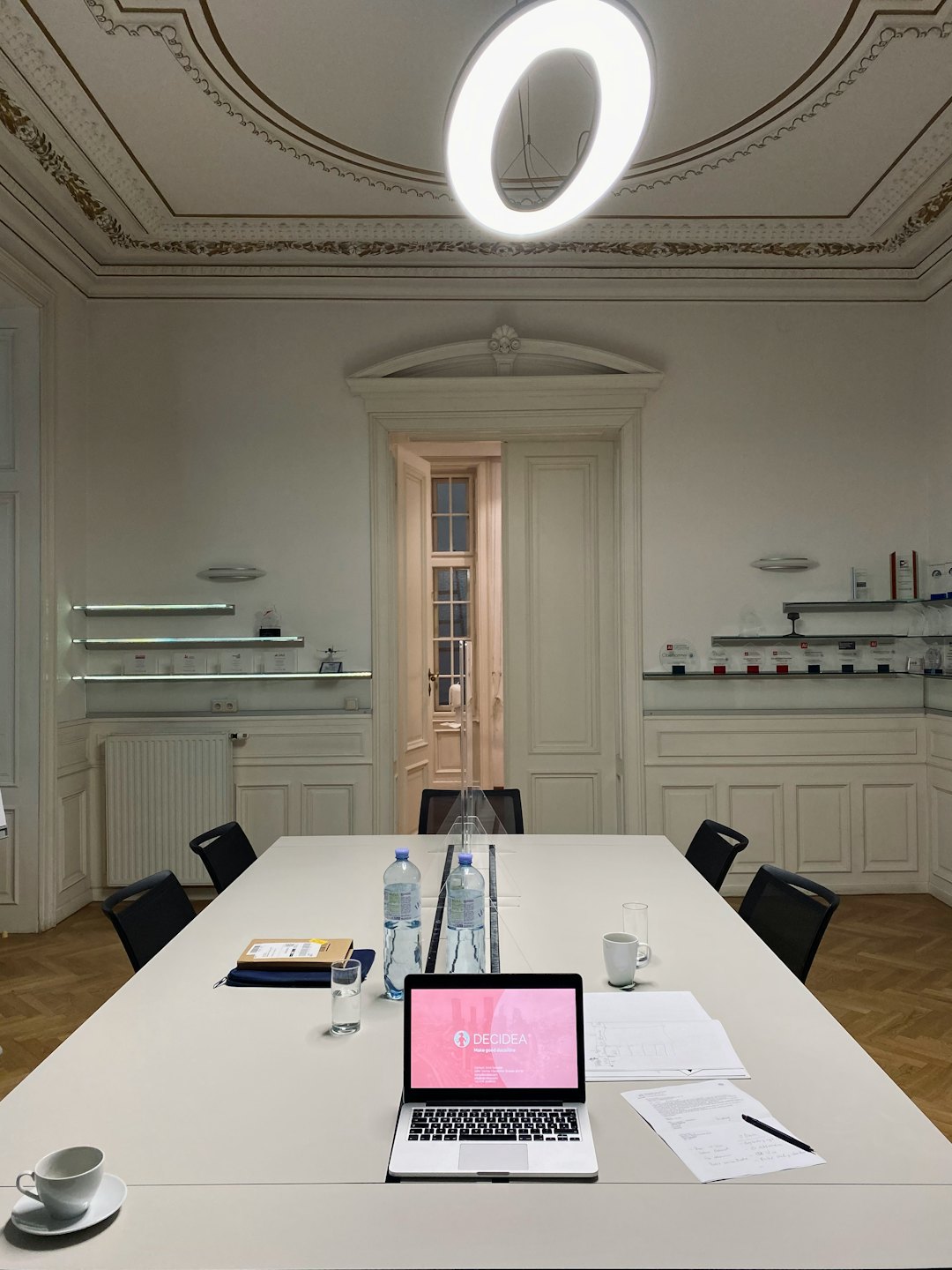 Sala de conferencias vacía con un portátil abierto sobre una mesa de reuniones.