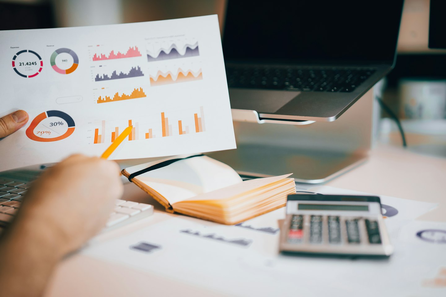 Persona analiza gráficos de datos empresariales con un lápiz amarillo sobre un escritorio.