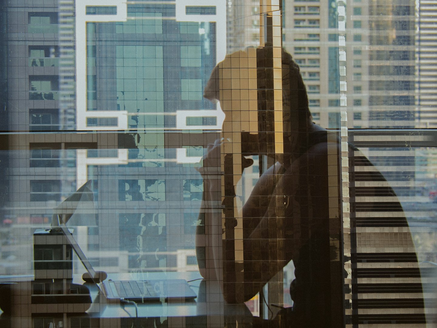 Profesional trabajando en un portátil con vistas a un moderno horizonte urbano.